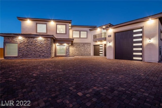 view of front facade featuring stone siding, stucco siding, and decorative driveway