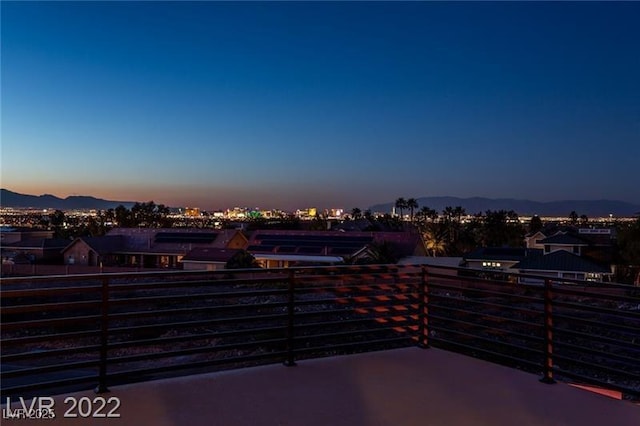 patio terrace at dusk with a mountain view, a balcony, and fence