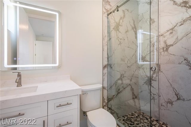 bathroom with vanity, toilet, and a marble finish shower