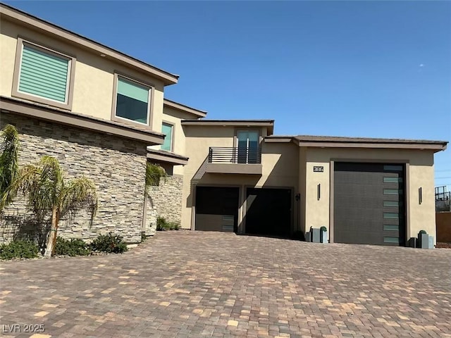 view of front facade featuring a balcony, decorative driveway, and stucco siding