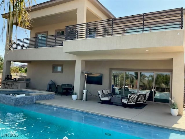 rear view of house with an outdoor kitchen, a patio area, stucco siding, outdoor lounge area, and a balcony
