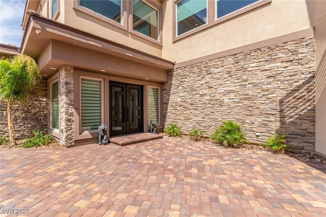 doorway to property with stucco siding and stone siding