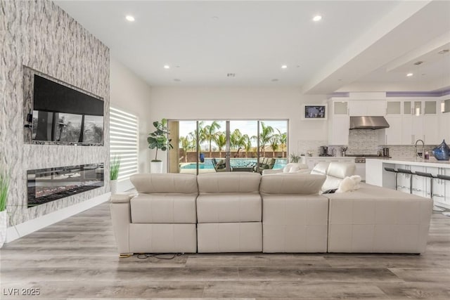 living area featuring a fireplace, light wood-style flooring, and recessed lighting