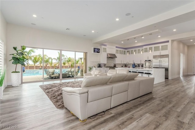living area featuring recessed lighting, baseboards, and light wood-type flooring