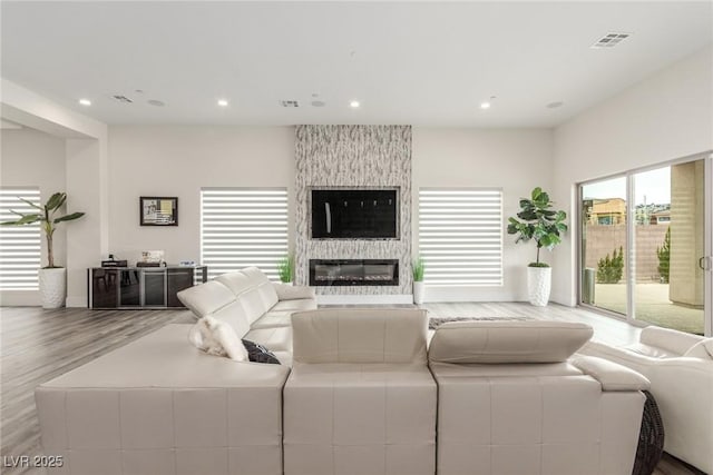 living area featuring a fireplace, visible vents, recessed lighting, and wood finished floors