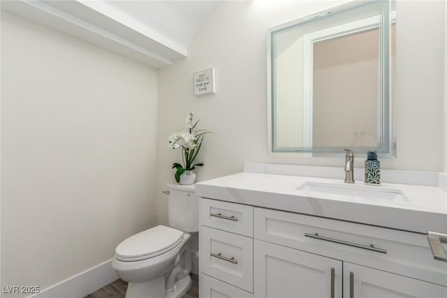 bathroom with baseboards, toilet, and vanity