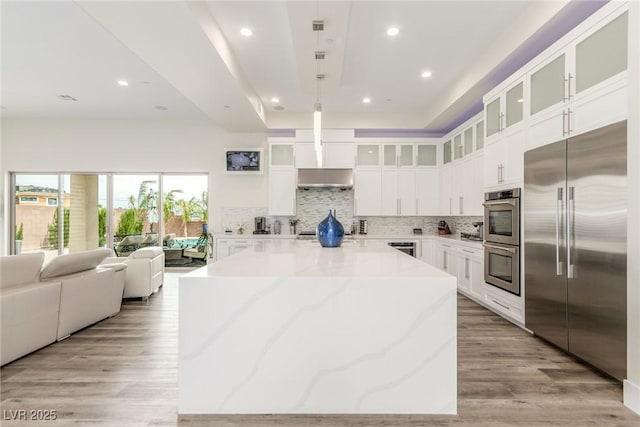 kitchen with open floor plan, tasteful backsplash, a center island, light wood finished floors, and appliances with stainless steel finishes