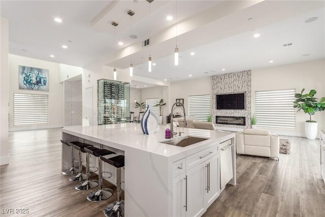 kitchen featuring a sink, pendant lighting, white cabinetry, wood finished floors, and open floor plan