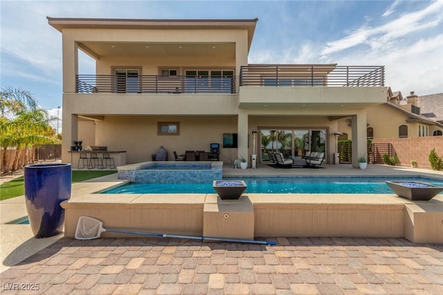 rear view of house with stucco siding, fence, a balcony, a fenced in pool, and an in ground hot tub