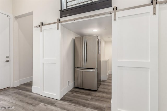 kitchen with a barn door, visible vents, wood finished floors, and freestanding refrigerator