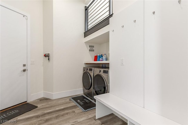 washroom with baseboards, washer and dryer, laundry area, and wood finished floors