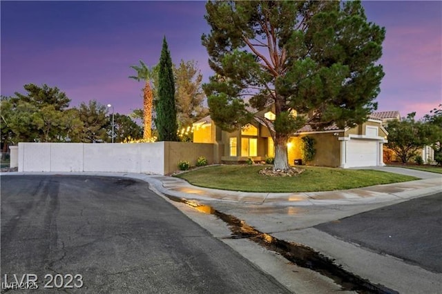 view of front of property featuring fence, a yard, stucco siding, concrete driveway, and a garage