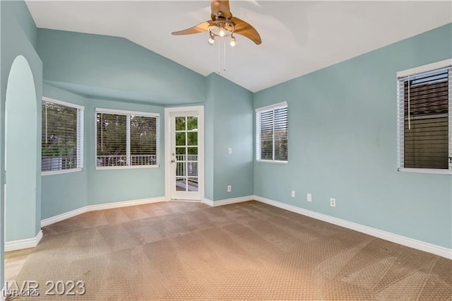 carpeted empty room with baseboards, ceiling fan, and vaulted ceiling