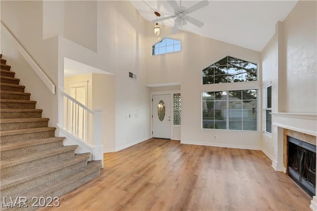 foyer with visible vents, a ceiling fan, wood finished floors, stairway, and a fireplace