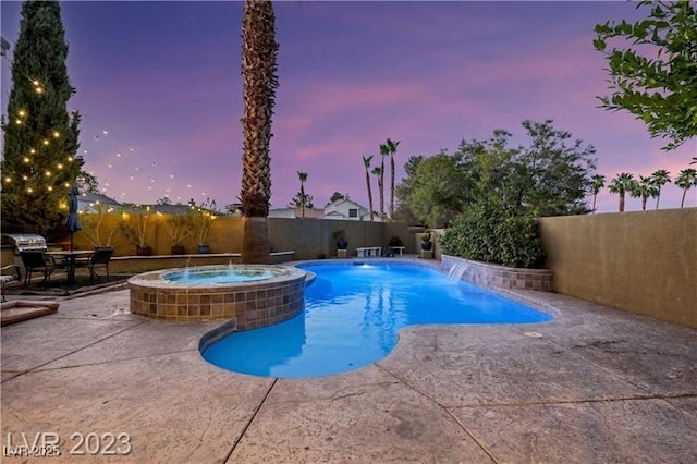 pool at dusk featuring a patio, a fenced backyard, a pool with connected hot tub, and a grill