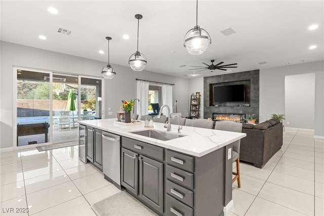 kitchen featuring visible vents, gray cabinetry, a kitchen island with sink, a sink, and light tile patterned flooring