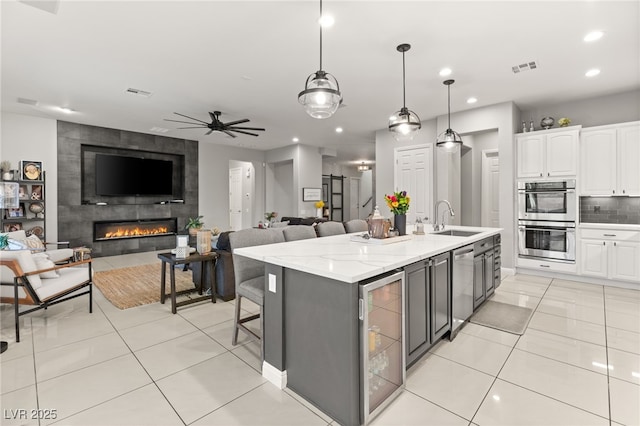 kitchen featuring beverage cooler, a sink, tasteful backsplash, appliances with stainless steel finishes, and white cabinets