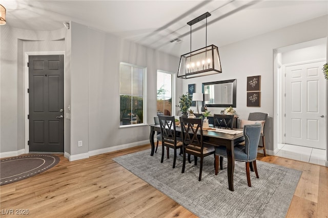 dining room featuring an inviting chandelier, visible vents, baseboards, and wood-type flooring