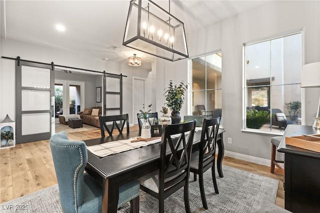 dining space with a barn door, light wood-style flooring, and baseboards