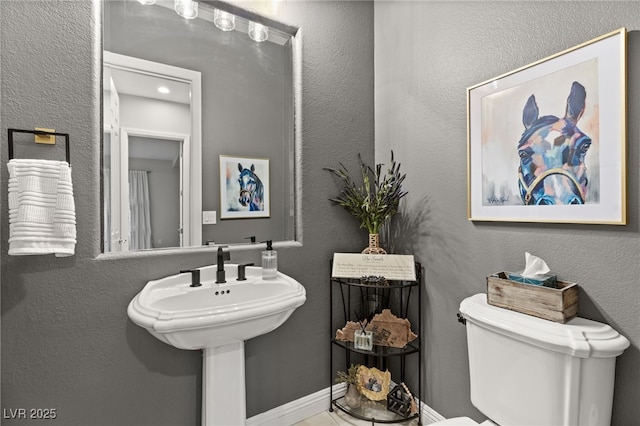 bathroom with toilet and a textured wall