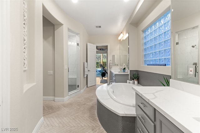 bathroom featuring visible vents, a shower stall, baseboards, a bath, and vanity