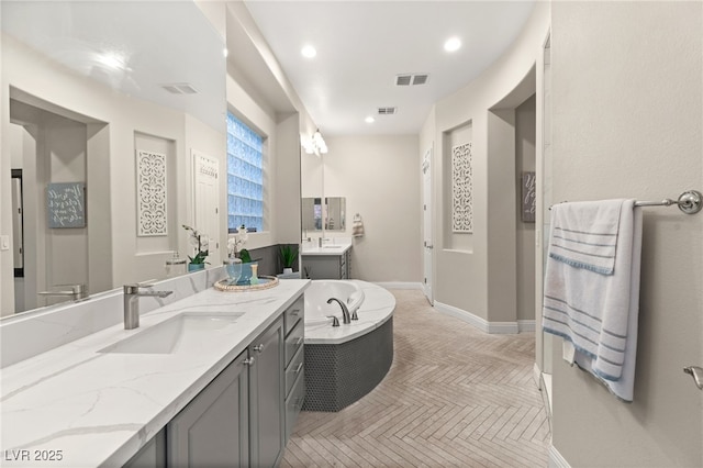 full bathroom featuring visible vents, two vanities, a sink, recessed lighting, and baseboards