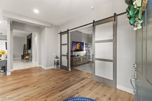 foyer with baseboards, a barn door, and wood finished floors