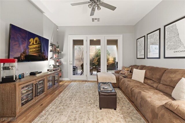 living room with a ceiling fan, wood finished floors, visible vents, and french doors