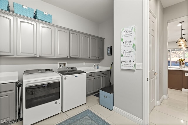 laundry room with light tile patterned flooring, cabinet space, independent washer and dryer, and a sink