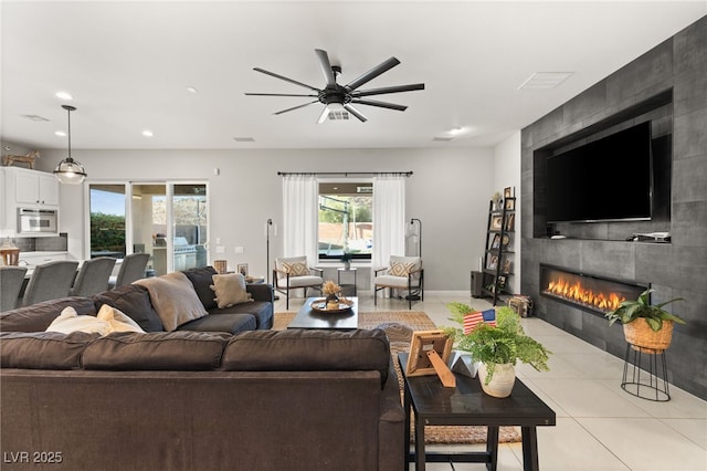 living room featuring a tiled fireplace, light tile patterned floors, recessed lighting, and a ceiling fan