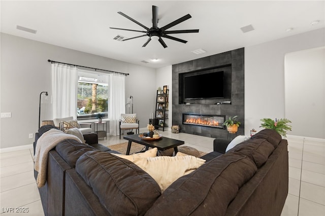 living area with light tile patterned floors, a fireplace, baseboards, and a ceiling fan