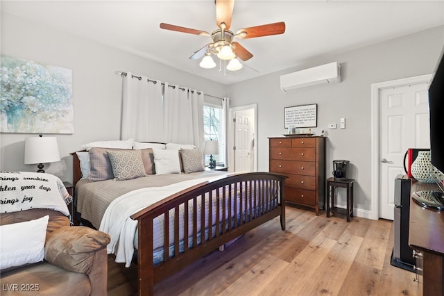 bedroom featuring light wood-style flooring, a ceiling fan, baseboards, and a wall mounted AC