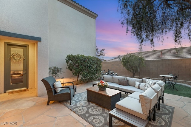 patio terrace at dusk with an outdoor hangout area and a fenced backyard