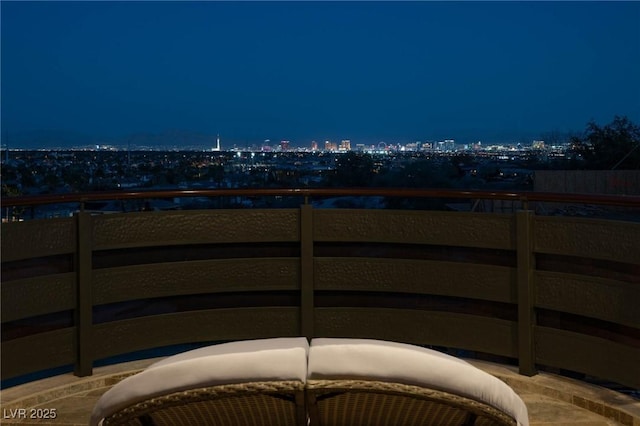 patio at twilight with a view of city lights and fence