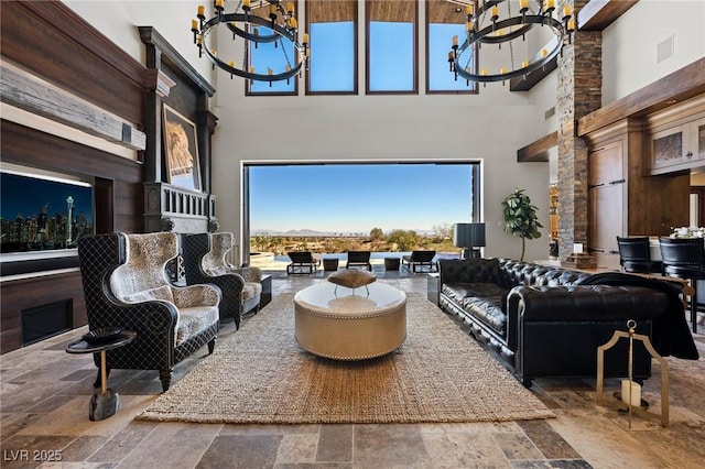 living area with stone tile flooring, a notable chandelier, and a high ceiling