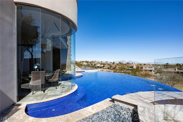 view of swimming pool featuring a jacuzzi, a patio, and an infinity pool