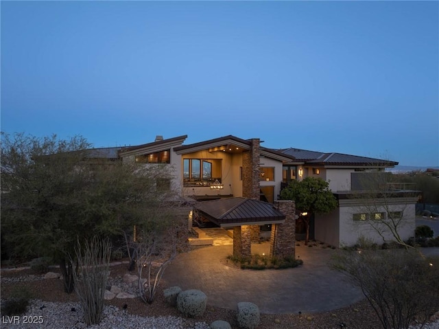 view of front of home featuring stucco siding, a patio, and a chimney