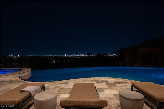 pool at twilight with a patio area and a pool with connected hot tub