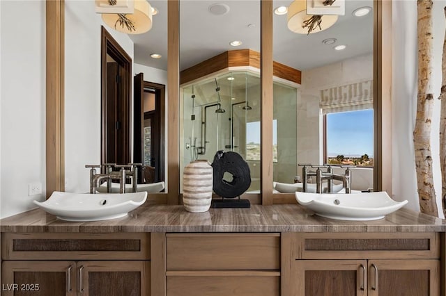 bathroom with double vanity, a shower stall, and a sink