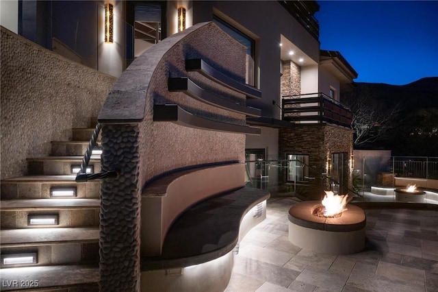 64 Promontory Ridge Dr, Las Vegas, NV 89135 - patio at night featuring an outdoor fire pit, a balcony, and a patio area