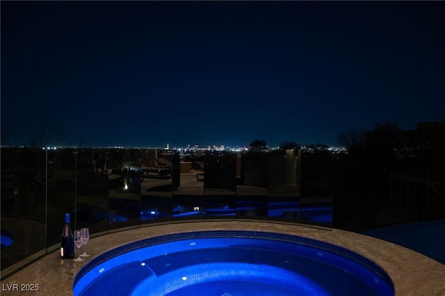 pool at night featuring an in ground hot tub and a patio area