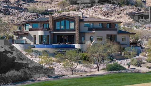 64 Promontory Ridge Dr, Las Vegas, NV 89135 - back of house with stucco siding, a balcony, a mountain view, and a chimney