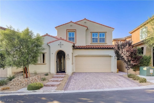 mediterranean / spanish home with stucco siding, a tiled roof, an attached garage, and decorative driveway