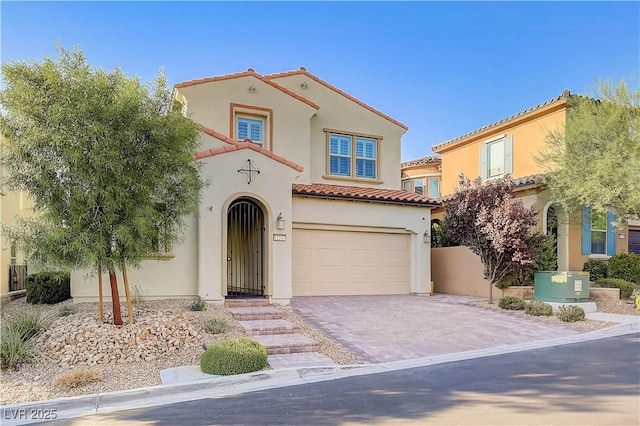 mediterranean / spanish house featuring a tiled roof, an attached garage, driveway, and stucco siding