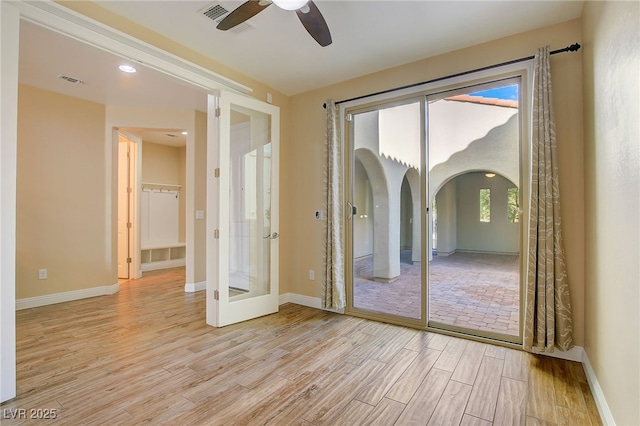 unfurnished room with arched walkways, light wood-style flooring, baseboards, and ceiling fan