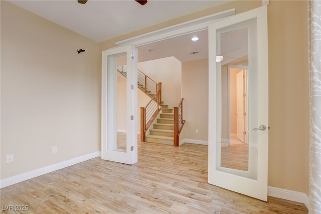 spare room with stairway, baseboards, and light wood finished floors