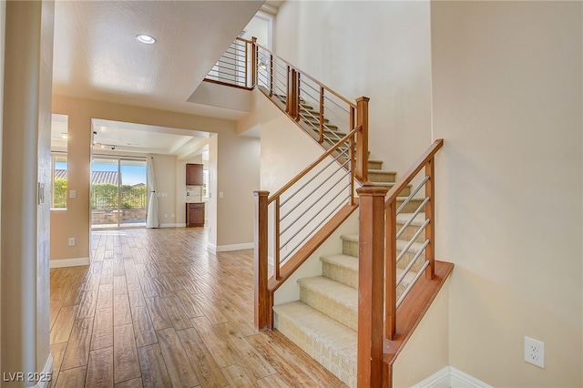 staircase with recessed lighting, wood finished floors, and baseboards