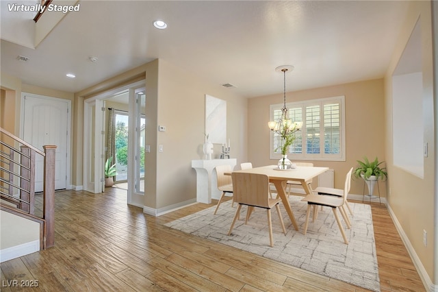 dining area featuring a chandelier, light wood-style flooring, stairs, and baseboards