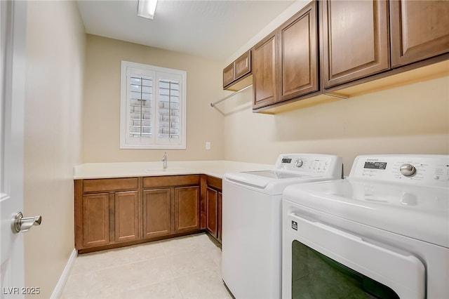 laundry area featuring a sink, cabinet space, separate washer and dryer, and light tile patterned flooring