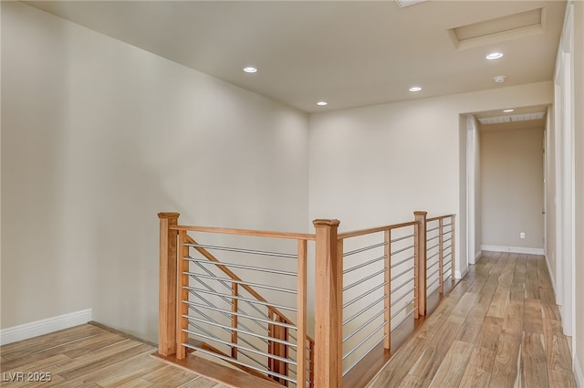 hall with baseboards, attic access, an upstairs landing, recessed lighting, and wood finished floors